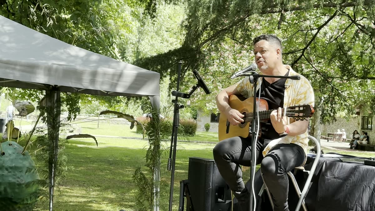 Auri Toledo tocando en un escenario íntimo con mesas iluminadas por velas al fondo