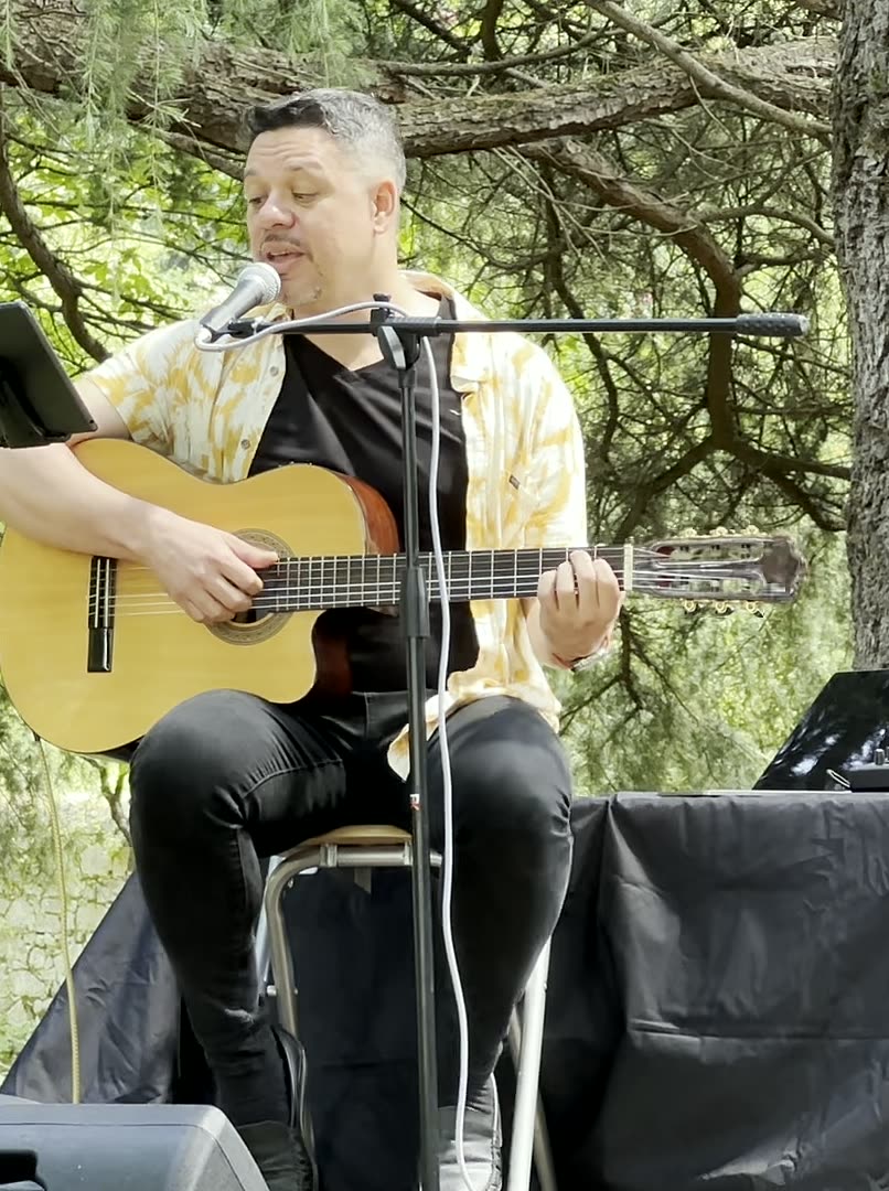 Auri Toledo cantando junto a un micrófono de cinta con los ojos cerrados