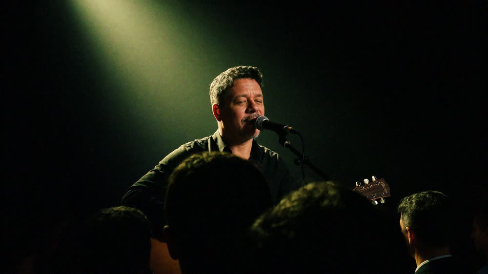 Auri Toledo en el escenario de una sala, bajo un foco cálido